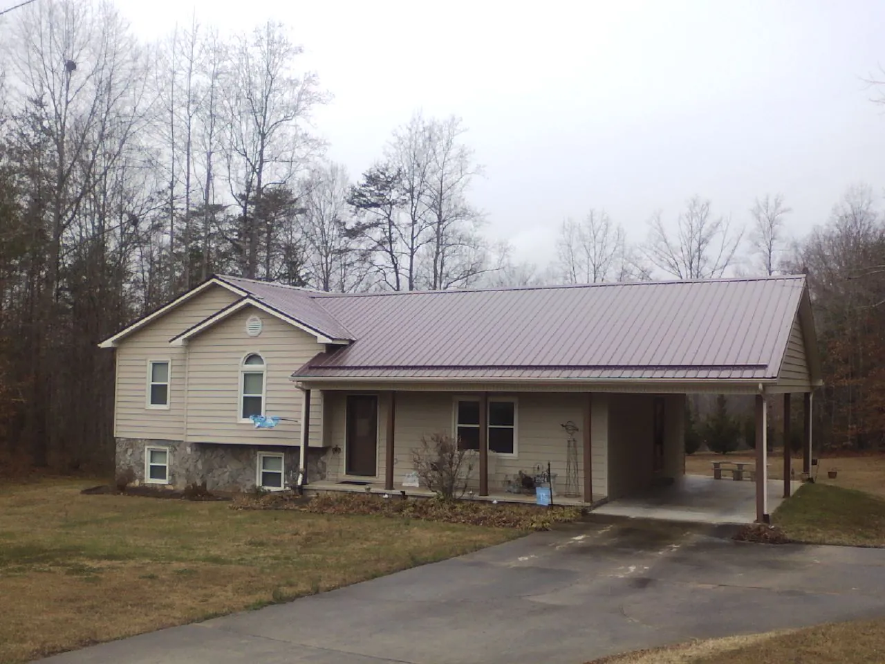 Burgundy metal roof on a tan split level home with an attached carport in Harrison